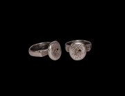 Medieval Silver Ring with Entwined Motif
13th-15th century AD. A silver D-section hoop, angled shoulders with incised lines, raised discoid bezel wit...