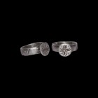 Post Medieval Silver Ring with Floral Cross
17th-18th century AD. A silver ring with wide hoop decorated with incised S-motifs, raised circular bezel...