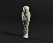 ARQUEOLOGÍA. EGIPTO. Baja Época. Ushebti con epígrafe y barba postiza (664-332 a.C.). Fayenza. Altura 11,7 cm. Presenta concreciones.