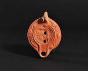 ARQUEOLOGÍA. ROMA. Lucerna con decoración de Sol en cuadriga a izq. (ss. II-III d.C.). Terracota. Longitud 11,5 cm.