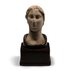 Ptolemaic Period, 323-30 B.C. Modelled in the half-round in Hellenistic style with a stephane and centre-parted hair, serene facial features including...