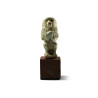 Late Period, 664-332 B.C. Modelled in the round as the god in baboon-form crouching holding a wedjat-eye in his forepaws; ribbed suspension loop on ba...