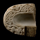 6th century A.D. Tongue-shaped with low rounded pad on the underside, raised edge with low-relief decoration of grape vines and leaves, the edge with ...