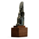 Late Period, 26th Dynasty, circa 664-525 B.C. The god modelled seated on a throne with a dorsal pillar, hands resting on his knees, wearing a short ki...