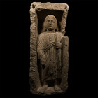 3rd-4th century A.D. Modelled in the half-round as a man standing on an integral plinth, round face with short curly hair, wide eyes, a slender nose a...