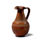 8th-7th century B.C. Globular body decorated with circumferential banding, low foot, conical neck with pinched spout, strap handle to the rear. 395 gr...