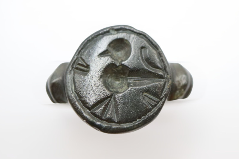 Bronze ring with a solid band and a large oval bezel decorated with stylized ima...