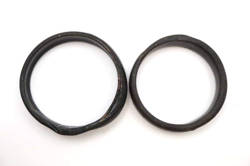 A pair of black glass, annular bracelets; 78.20 grams in total,72.40 and 76mm. C...