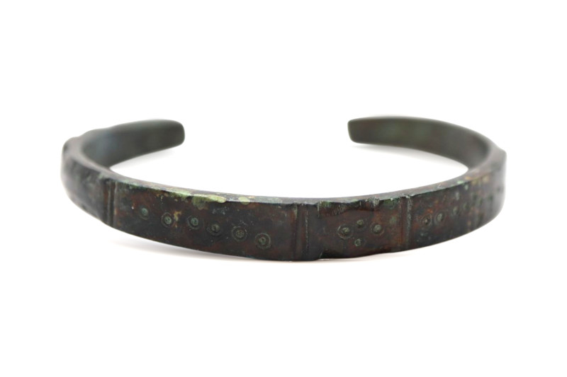 A solid bronze bracelet with overall decoration displays a distinguished geometr...