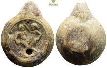 Roman. Terracotta oil lamp. 2nd-3rd centuries AD. (45.05g, 72.1mm). A simple round, post-volute type oil lamp with a small spout and two holes. On the...