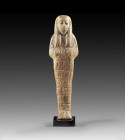 Shabti of Machu. New Kingdom, 19th dynasty, time of Ramses II, ca. 1279-1213 BC. Wood. H 21cm. Mummy-shaped with a tripartite wig and two ploughs in h...