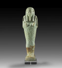 Shabti of Ikaros. Turquoise faience, H 17.4cm. Late Period, 30th dynasty about 359 - 341 BC. Mummy-shaped with a back pillar, a tripartite wig, a bear...