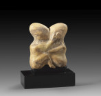 A somewhat flattened, round, sculptural group made of calcite consisting of two childlike, naked figures with elongated backs of the heads, squatting ...
