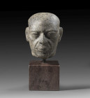 A fascinating granodiorite head of a bald man, probably a priest, below life-size, slightly elongated with signs of age and full lips. Late Period, ab...
