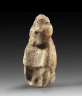 An alabaster figurine of a crouching hamadryas baboon with a crescent moon and lunar disk on its head. On its chest is the cartouche of Queen Tiye, Ti...