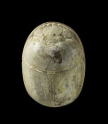 A large white scarab made of steatite with hieroglyphic inscription framing the depiction of a phoinix wearing the hemhem crown. The inscription is no...