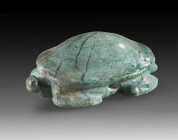 Amulet in the shape of a Nile tortoise. L 3cm. Made from grey-greenish mafite. Smooth on the underside. Hole drilled across the body for suspension. H...