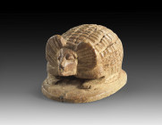Amulet in shape of a hedgehog made of brownish steatite with longitudinal drilling, on the underside of the oval plinth a perch with two lotus flowers...