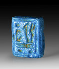 Faience bead of the reign of Tawosret: L 2.2cm, W 1.8cm, D 0.5cm. Made of blue faience with longitudinal drilling. Rectangular foundation deposit plaq...