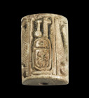 Amulet in the shape of a halfcylinder made of light brown steatite with longitudinal drilling, H 2cm. On the top: the throne name of Amenophis II (= A...