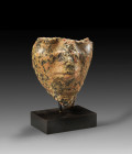 A fragmentary head of a pharao(?) made of red Assuan granite. Preserved is the lower part of the face with small parts of the beard. Fragmentary, nose...