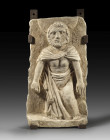 Limestone relief depicting a bearded man wearing a mantle that covers his hips, legs and shoulders. The figure is nimbate and therefore depicts a Sain...