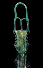 Double kohl tube. Eastern Mediterranean, 4th - 6th century AD. H 24cm. Bluish translucent glass. U-shaped body from two tall tubes, with tubular rims,...