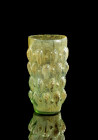 Almond cup. Eastern Mediterranean, 1st half 1st c. AD. H 12,7cm. Greenish clear glass. Conical, mould-blown body with almond-shaped knobs. Cracks in t...