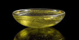 Hellenistic glass bowl with flat body. H 4,7cm, ø 16cm. Olive green clear glass. Two deep grooves below rim on inside, two superficial grooves on bott...