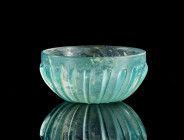 Blue-green ribbed glass bowl. ø 11,2cm; H 5,3cm. Roman, 1st century BC - 1st century AD. Broad ribs on exterior runnig down to the center. Traces of s...