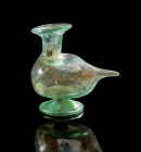 Bird-shaped funnel. Eastern Mediterranean, 1st - 2nd century AD. H 7,7cm, L 8,5cm. Green translucent glass. Bag-shaped body with foot, tall cylindrica...
