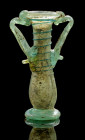 Zweihenkeliges Balsamarium mit Fadendekor. ca. 4. Jh. n. Chr. H 11,1cm. Tropfenförmiges Salbgefäß aus grünlichem Klarglas mit Trichteröffnung, zwei He...