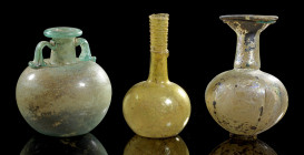 Drei Gläser. Römisch, 2. - 4. Jh. n. Chr. a) Gerippter Sprinkler mit Füßchen. H 13cm. Farbloses Glas mit grünem Ring am Ausguss, irisierend. b) Arybal...