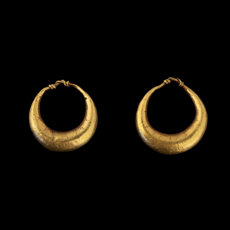 AN EGYPTIAN PAIR OF GOLD CRESCENT-SHAPED EARRINGS.
New-Kingdom, Dynasty 18, 155...