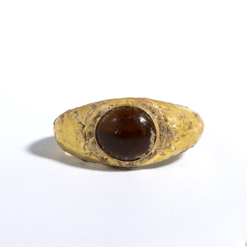 *A ROMAN GOLD RING SET WITH AN ORANGE GARNET.
1st century A.D.
Diam. 2,2 cm
...