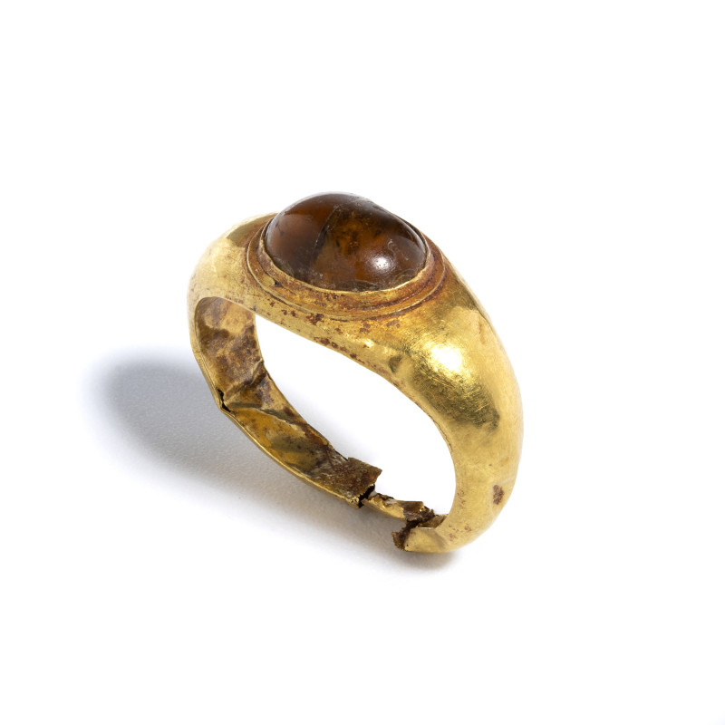 *A ROMAN GOLD RING SET WITH A ORANGE CABOCHON GARNET.
Ca. 1st century A.D.
Dia...