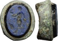 Bronze ring bezel with glass paste intaglio depicting standing figure.
 Roman period, 1st-3rd century AD.
 16 x 14 mm.