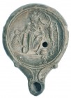 ROMA. Lucerna. Siglo II-III d.C. Cerámica. Representa figura masculina sentada con túnica y un mono a su derecha. Longitud 10,5 cm.