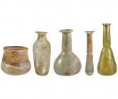 ROMA. Lote de cuatro ungüentarios y un vaso. Siglo II-III d.C. Vidrio con irisaciones. Altura 4,5; 9,5; 12,0; 10,5 y 12,0 cm.